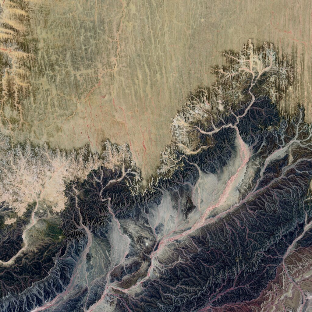 Terre vue du ciel : territoire aride, entre glace jaunie et terre brune, des ramifications liquides figées par une vague de froid.