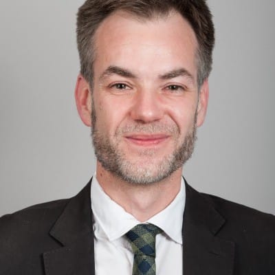 Photographie de Jean-Philippe Vinquant. Cheveux courts et légère barbe grise, en costume noir, il sourit à la caméra.