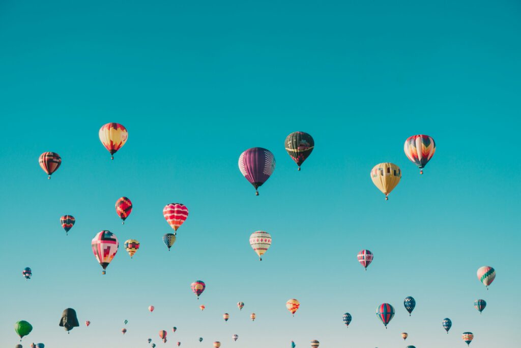 Image d'illustration : photographie de montgolfières s'élevant dans un ciel bleu azur.